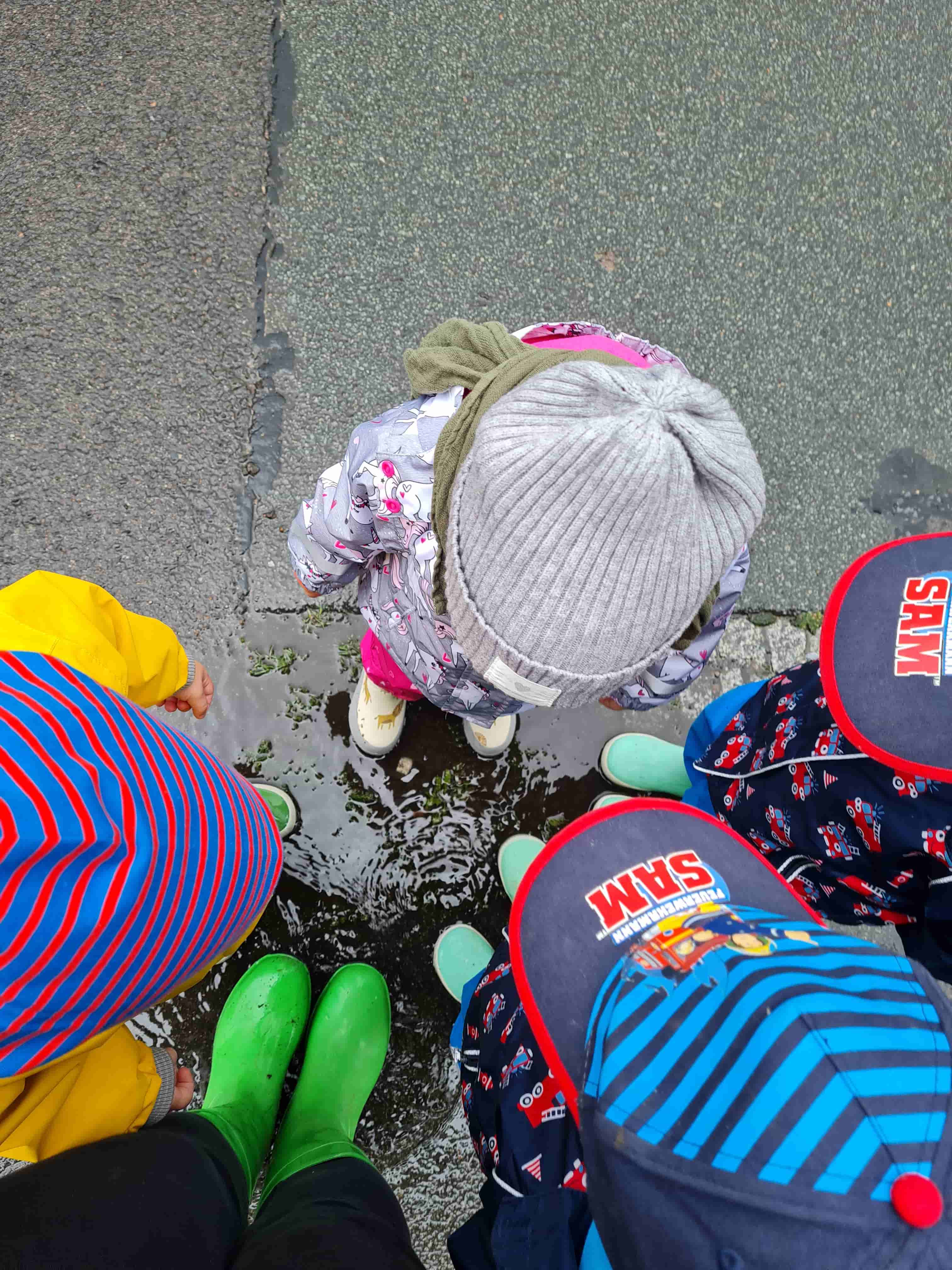 Kinder stehen um Pfütze rum