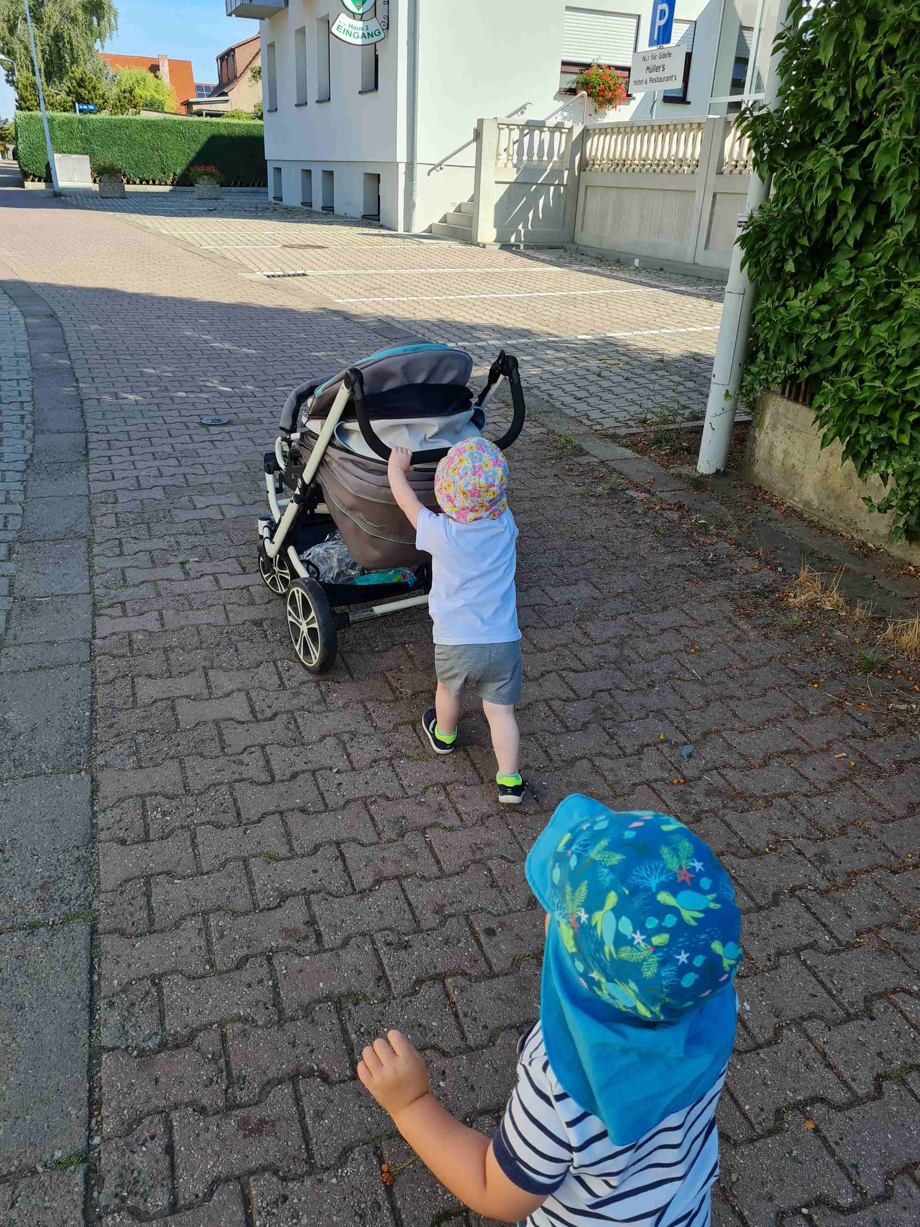 Kind schiebt Kinderwagen